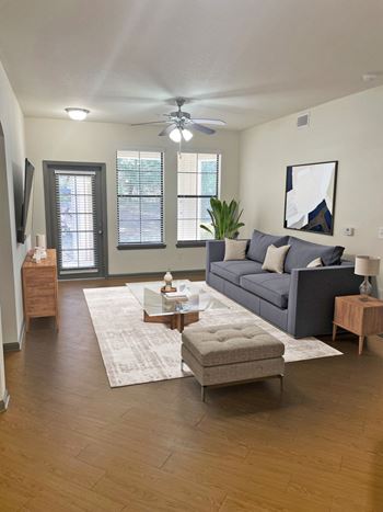 A living room with a grey couch, a coffee table, and a ceiling fan.